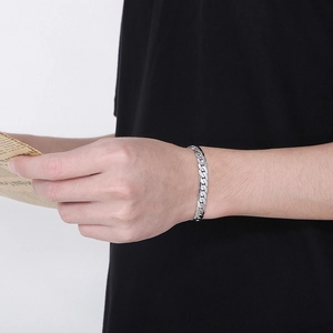 Detail of silver stainless steel flat Cuban link chain bracelet on male model wrist