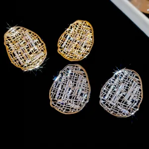 Boucles d'oreilles ovales évidées en or et argent avec zircons sur fond noir