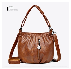 Detail view of brown pleated crossbody bag with metal kangaroo pendant and zipper
