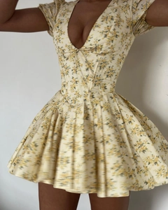 Détail de la robe courte fleurie jaune avec décolleté en V profond et ourlet plissé fluide