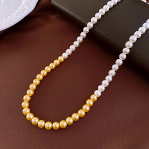 Vintage French-style pearl necklace with white and gold beads on dark textured fabric