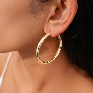 Close-up of elegant large golden hoop earring worn by a model with a radiant finish