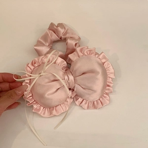 Nahaufnahme eines süßen rosa gerüschten herzförmigen Haargummis mit Satin-Finish-Detail