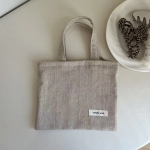 Detail of oat-colored linen mini tote bag featuring the simple wish stitched fabric label