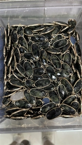 Detailed view of faceted oval crystal connectors with gold plated edges in a clear box