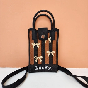Detailed texture of knitted crossbody bag featuring pixelated bow pattern and Lucky. text
