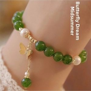Macro view of jade and pearl beaded bracelet featuring a gold butterfly pendant