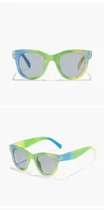 Close-up of glittery round kids sunglasses with rainbow gradient frame and grey lenses