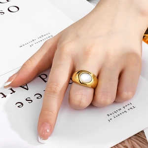 Detail of a gold ring with white oval opal gemstone worn by a model in a luxury setting