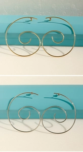 Macro view of minimalist spiral gold and silver hoop earrings in a blue gift box