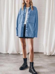 Detail view of a loose denim shirt with large front pockets and button-down styling