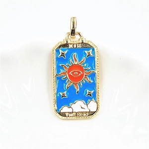 Detailed macro of golden THE SUN tarot card pendant with blue enamel and sun design