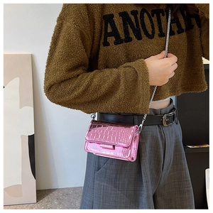 Detail of mini pink crocodile textured leather bag with metallic silver chain strap