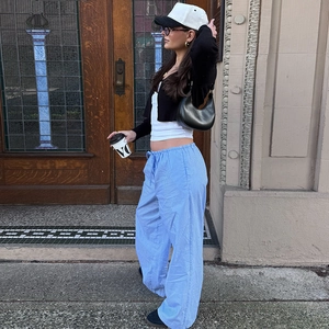 Straßenstil-Ansicht der blau-weiß gestreiften weiten Hose mit schwarzer kurzer Strickjacke
