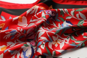 Detail van rode zijden sjaal met bloemen, vlinders en elegante satijnen plooien