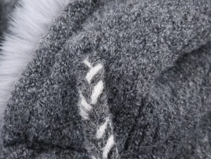Detail of gray knit fabric with white cross-stitch and soft faux fur trim texture