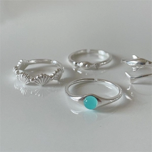 Detailed view of silver marine rings featuring shell relief and turquoise stone