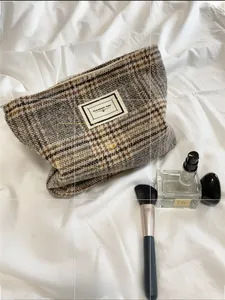 Close-up of a plaid toiletry bag with Pleasant Time label on soft white bedding