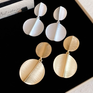 Detail view of gold and silver brushed metal circular earrings on a black display box