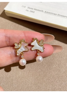 Détail de la boucle d'oreille licorne dorée avec nacre blanche et goutte de perle