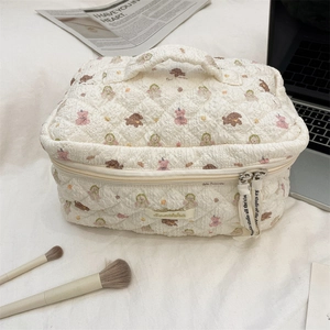 Close-up of quilted beige makeup bag with teddy bear pattern and zipper detail