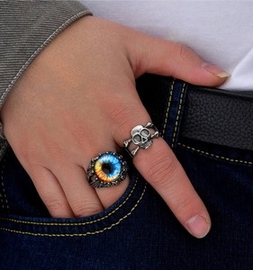 Detail of gothic devil eye and skull open rings worn with denim and leather belt