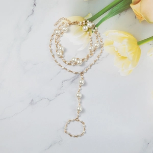 Bohemian gold chain hand harness with white pearls displayed on white marble with tulips
