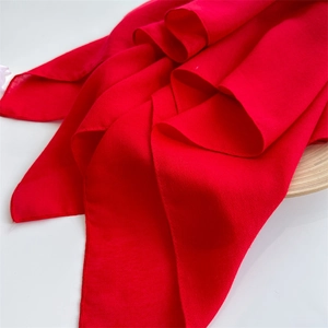 Close-up detail of soft red cotton linen scarf texture with elegant draping folds