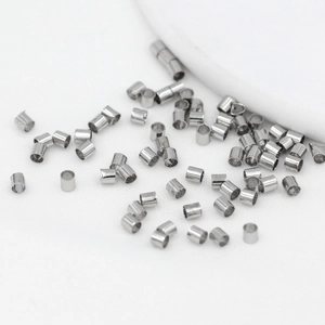 Close-up of silver-plated cylindrical spacer beads on white fabric for DIY jewelry