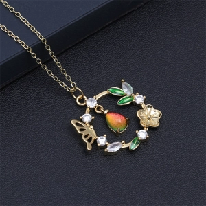 Vue macro du pendentif papillon et fleur dorée avec cristal à changement de couleur