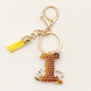 Detailed view of resin letter I keychain with golden bee, honeycomb, and yellow tassel