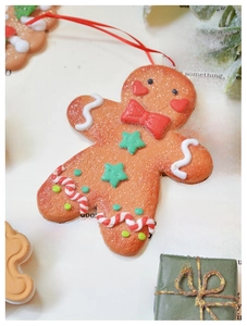 Detail of gingerbread man Christmas ornament with red bow on vintage book pages