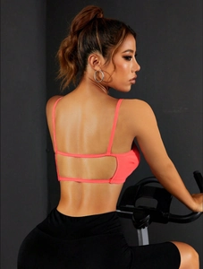 Détail des fines bretelles croisées sur une brassière de sport néon à texture côtelée