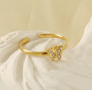 Detailed close-up of 18K gold-plated butterfly ring with white zircon stones on stone stand