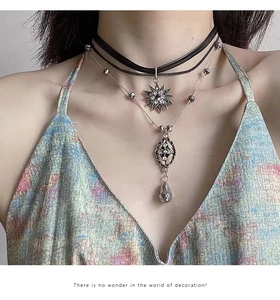 Detail of layered bohemian necklace with star pendants and grey teardrop crystal on model