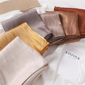 Detailed stack of multi-colored glossy satin scarves showing silk texture and shimmer