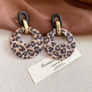 Close-up of leopard print acrylic round pendant earrings with golden metal details