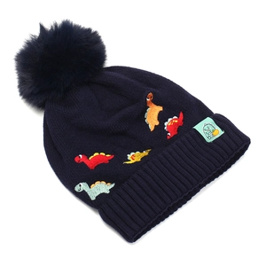 Détail du bonnet en tricot bleu marine avec broderies de dinosaures et pompon doux