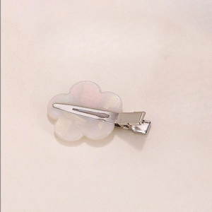 Detailed macro view of an iridescent white flower hair clip with metal alligator grip