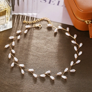 Detail of leaf vine pearl necklace with gold wire and teardrop pearls on leather