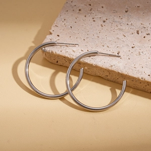 Close-up of silver C-shaped hoop earrings with a smooth metallic finish on a textured stone