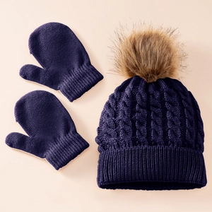 Detailed knit texture of dark purple winter hat with faux fur pom and matching mittens