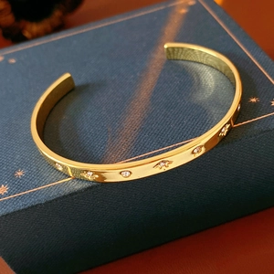 Détail d'un bracelet doré avec gravures étoilées et pierres en oxyde de zirconium