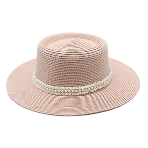 Detailed view of light pink straw hat featuring delicate white lace and pearl trim