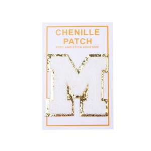 Close-up of white chenille patch letter M with gold glitter border and self-adhesive back