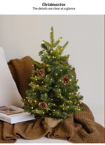 Close-up of a mini desktop Christmas tree with LED lights and pine cones on a knit rug