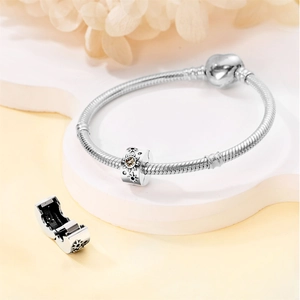 Detail of silver sun and moon pendant bead on a snake chain bracelet with heart clasp