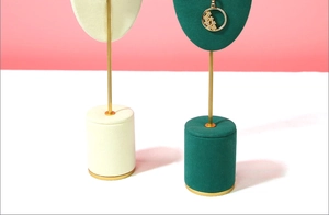 Microfiber jewelry display stands in beige and dark green with golden pendant details