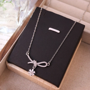 Silver bow necklace with zircon daisy tassel pendant on luxury display stand