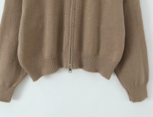 Detail of a brown knit cardigan with high-quality ribbed hem and a silver zipper closure